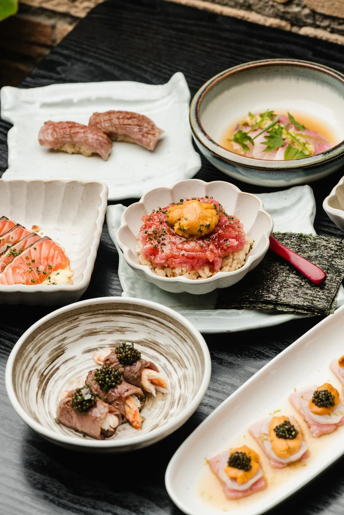 Gourmet Japanese spread featuring sashimi, uni, caviar, and seared fish.