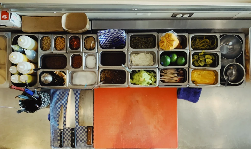 Organized professional kitchen prep station with ingredients and tools.