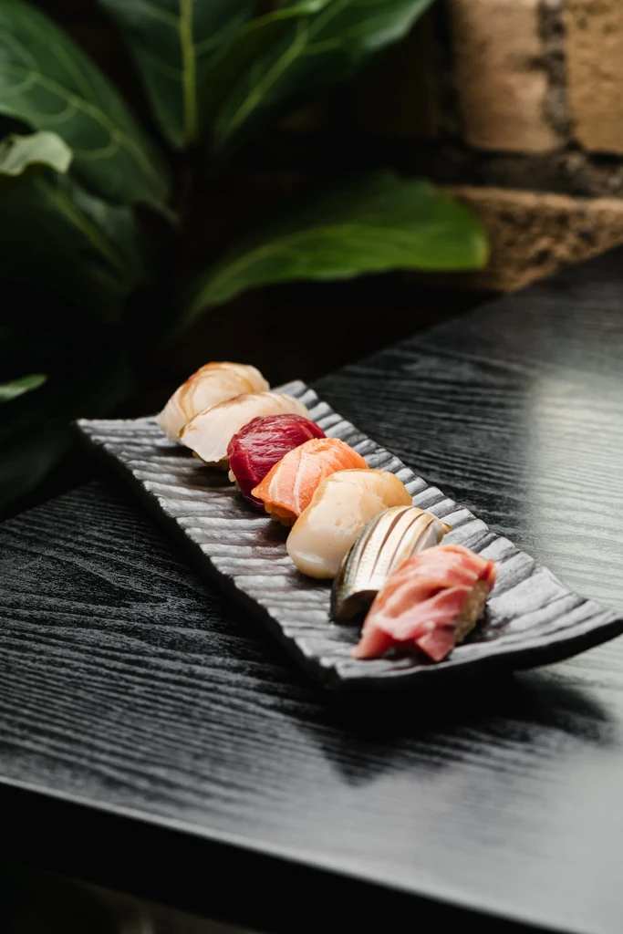 Six colorful nigiri sushi arranged on a dark grey plate.