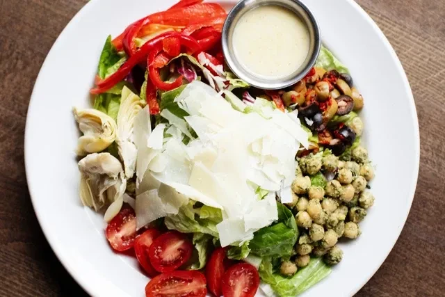 Vibrant salad with greens, vegetables, cheese, and dressing.