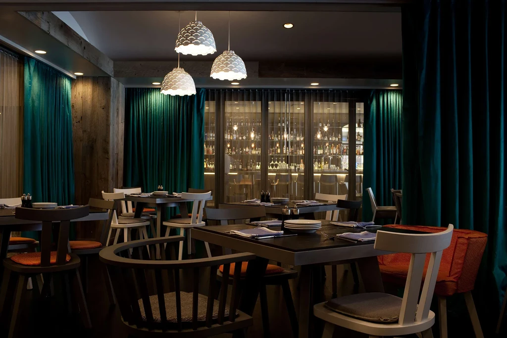 Elegant dining room with scallop pendant lights, teal curtains, and a bar.