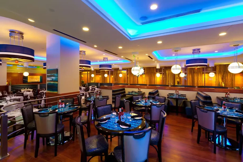 Modern empty restaurant interior with diverse seating, blue lights, and abstract pillar.