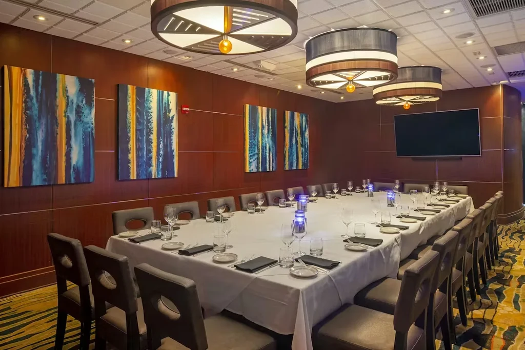 Modern private dining room with a long set table and abstract art.