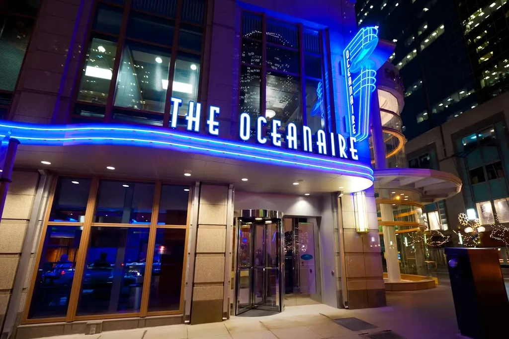 Night view of 'THE OCEANAIRE' restaurant, lit by blue neon signs.