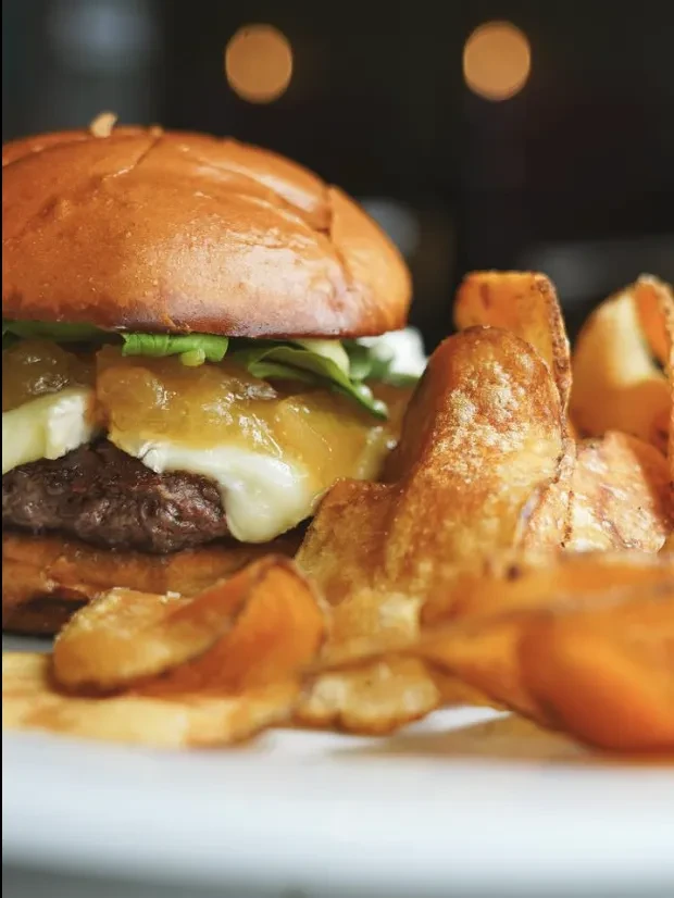 Gourmet beef burger with melted cheese and crispy chips.