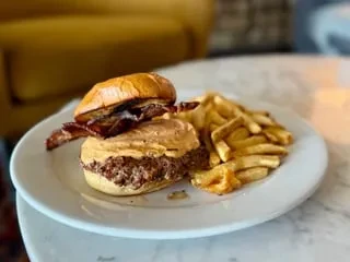 Gourmet burger with peanut butter and bacon, served with golden fries.