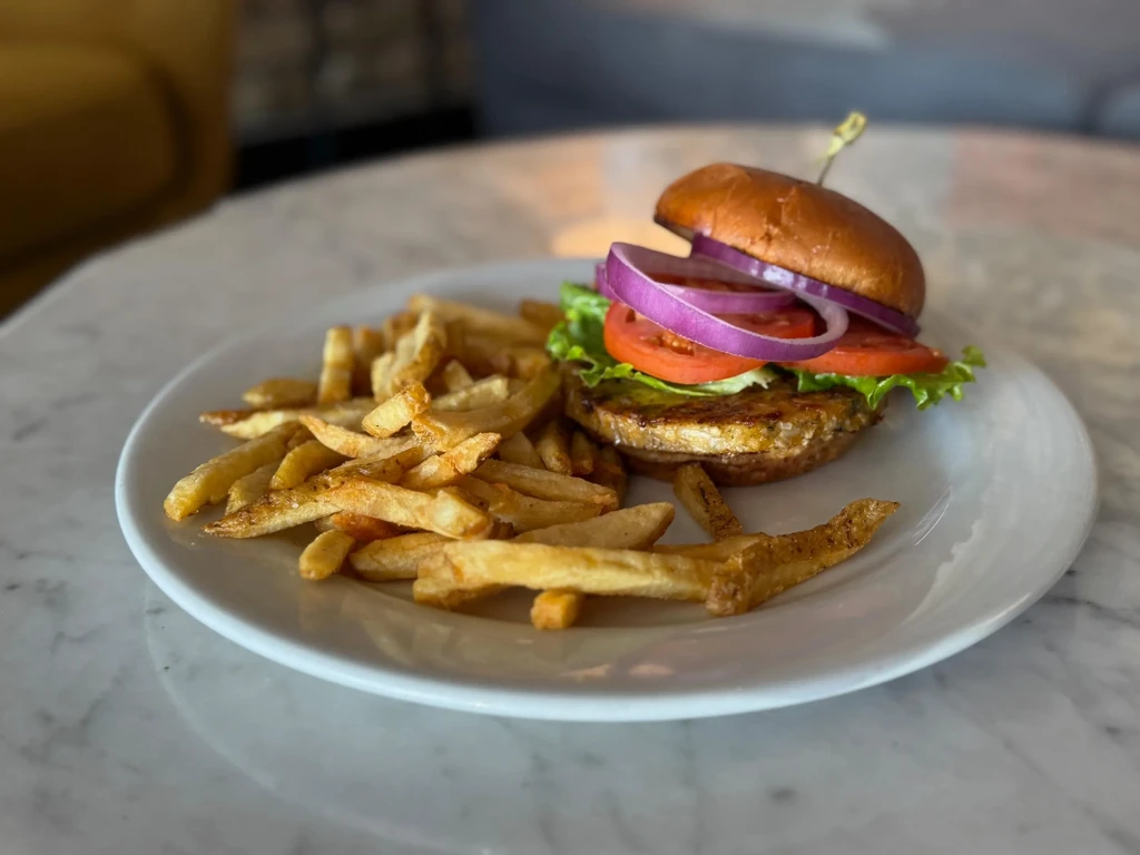 Open-faced burger, lettuce, tomato, onion, and golden fries on marble.