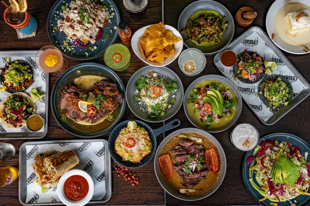 Vibrant top-down view of Sonora Grill Mexican food, tacos, and cocktails.