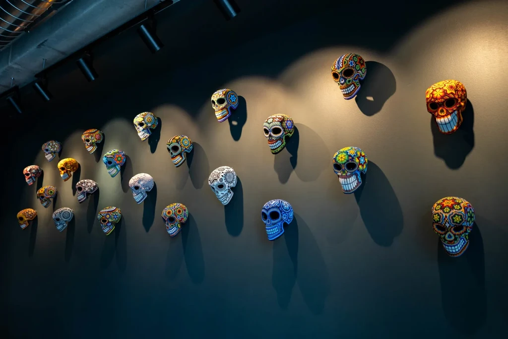 Numerous vibrant sugar skull masks displayed on a dark wall.