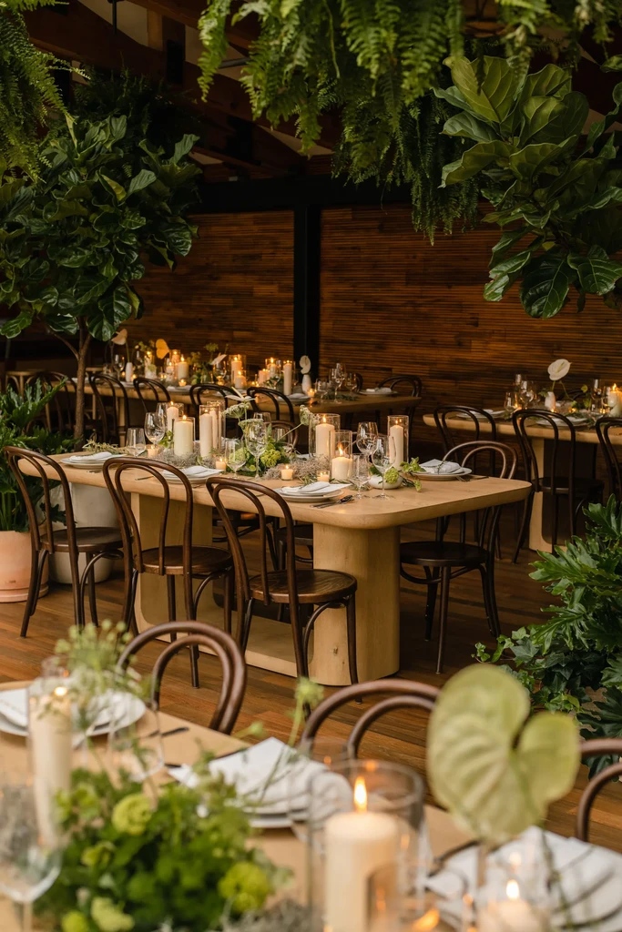Elegantly set long tables with lush greenery, candles, and bentwood chairs.