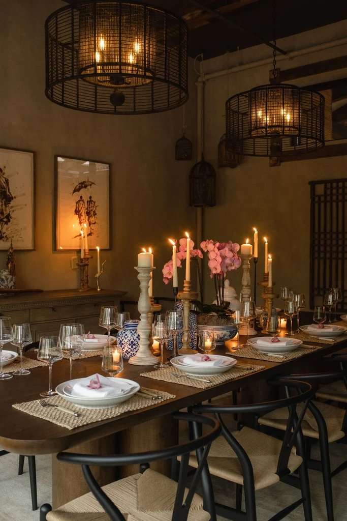 Elegant candlelit dining room with orchids, blue porcelain, birdcage chandeliers.