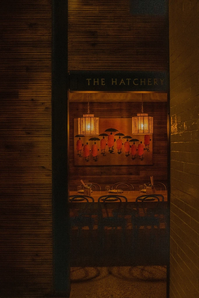 Warmly lit THE HATCHERY restaurant interior, with Asian art and table.
