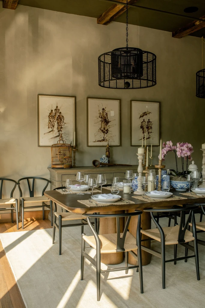 Elegant dining room: set table, wishbone chairs, chandelier, pink orchids.