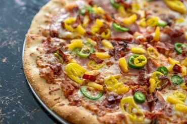 Close-up of a fully baked pizza with crispy crust and colorful toppings.