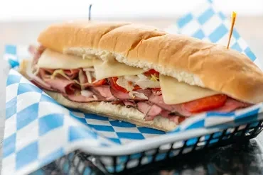 Submarine sandwich with roast beef, cheese, lettuce, tomatoes, in basket.
