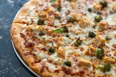 Freshly baked pizza with chicken, broccoli, and melted white cheese.