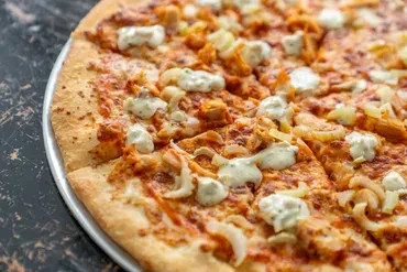 Buffalo chicken pizza with shredded chicken, onions, and creamy dressing.
