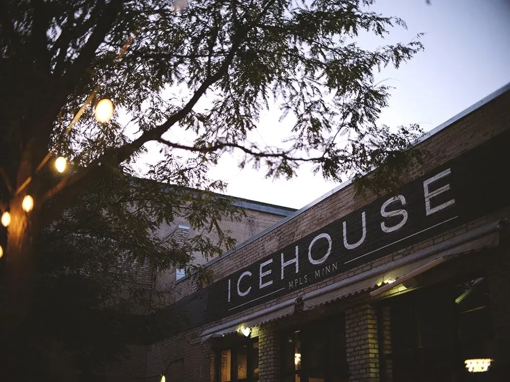 Dusk view of Icehouse restaurant with brick exterior and warm string lights.