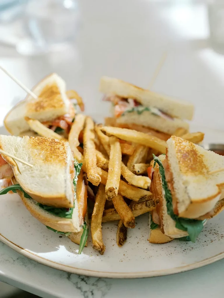 A plate of mini-sandwiches with meat, arugula, and golden french fries.