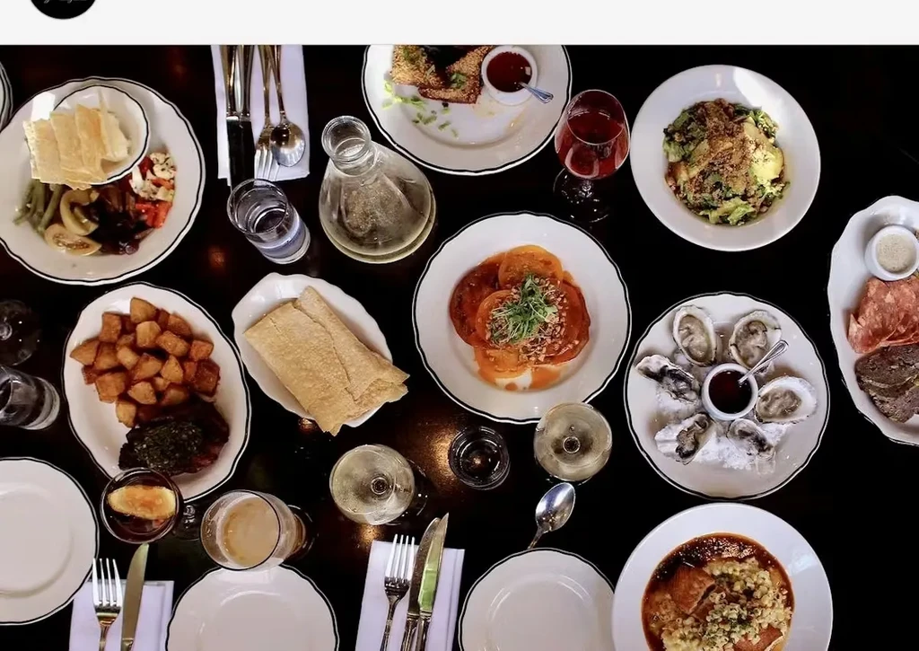 Vibrant overhead view of a multi-course meal on a dark dining table.