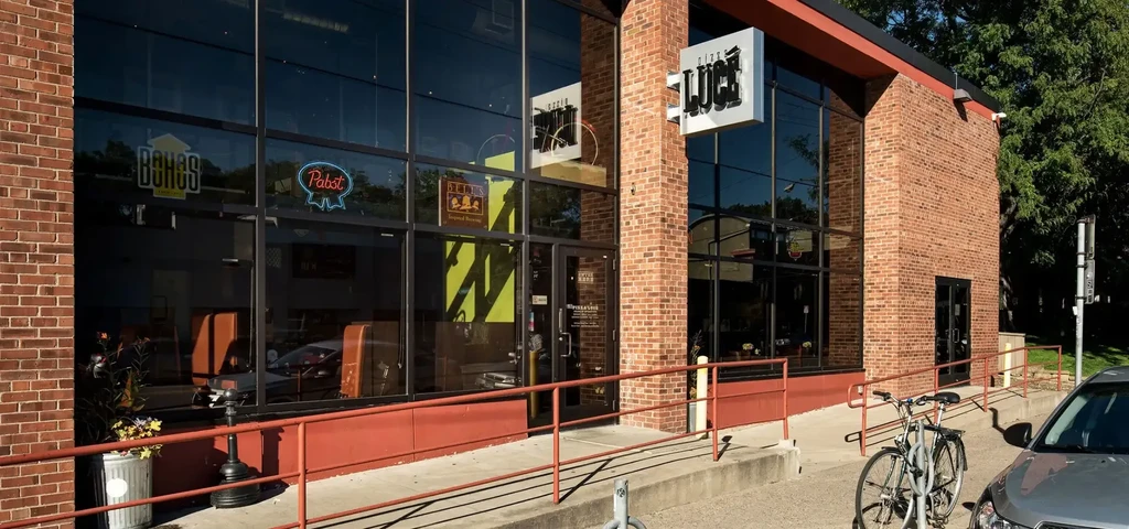 Pizza Lucé Pizzeria, a brick building with large tinted windows and ramp.