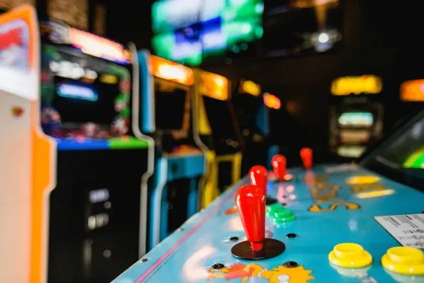 Arcade machine control panel with red joysticks, buttons, and character art.