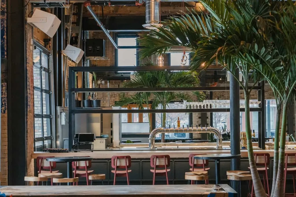 Industrial-chic bar interior with exposed brick, beer taps, and plants.