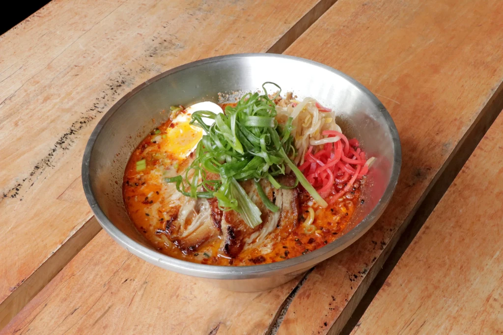 Close-up vibrant ramen bowl, egg, pork, scallions, red ginger.