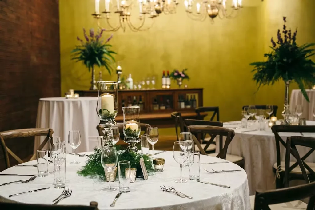 Elegant restaurant dining room with multiple meticulously set candlelit tables.