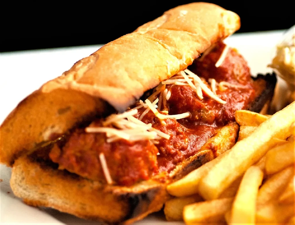 Meatball sub sandwich with marinara, cheese, and french fries.