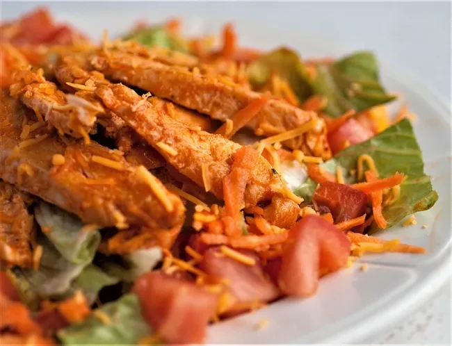 Cooked chicken salad with orange sauce, cheese, lettuce, tomatoes, carrots.