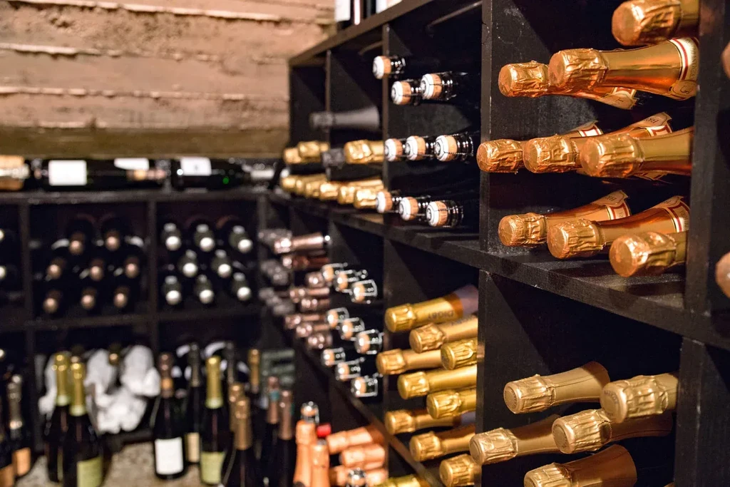 Champagne and wine bottles neatly stored in a dark wooden cellar.