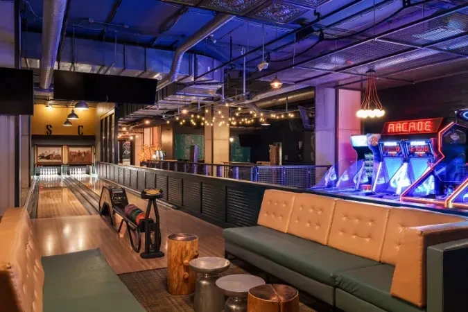 Industrial-chic entertainment space with bowling lanes, lounge, and arcade.