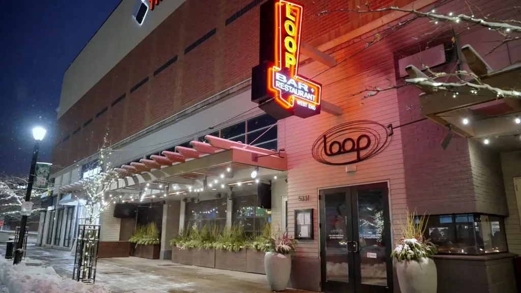 Well-lit 'the LOOP' restaurant exterior at night during a snowfall.