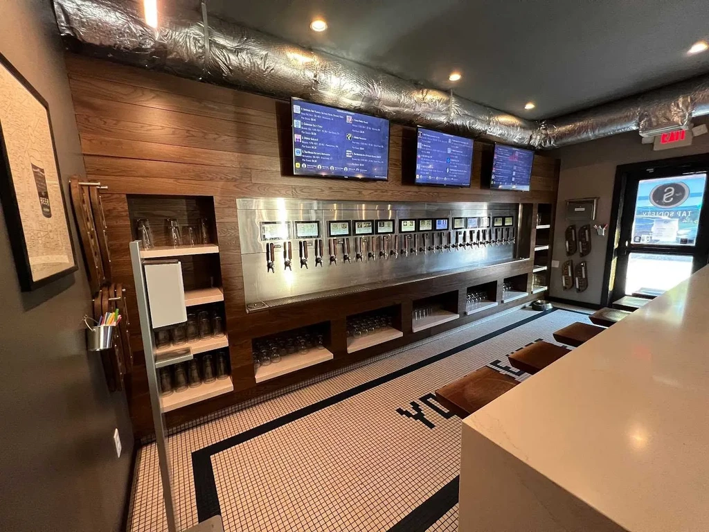 Self-pour taproom interior showing many taps, digital screens, and wood walls.