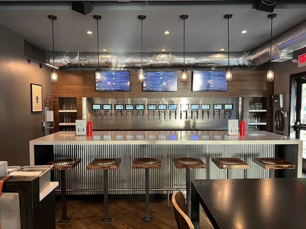 Empty, modern self-pour taproom with many digital taps and industrial design.