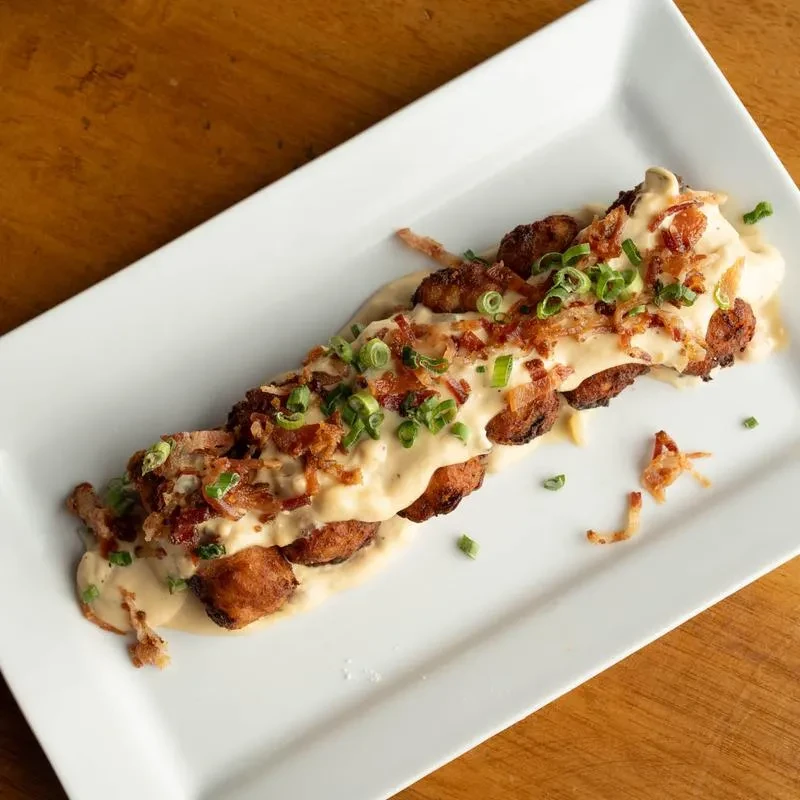 Tater tots with creamy sauce, crispy bacon, and green onions.
