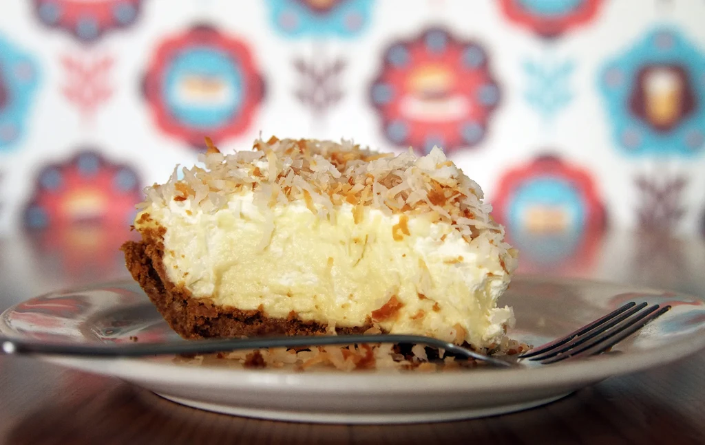 Slice of coconut cream pie with whipped cream and toasted coconut.