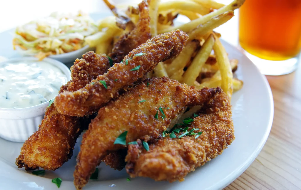 Golden fried fish/chicken and fries, with creamy sauce and coleslaw.