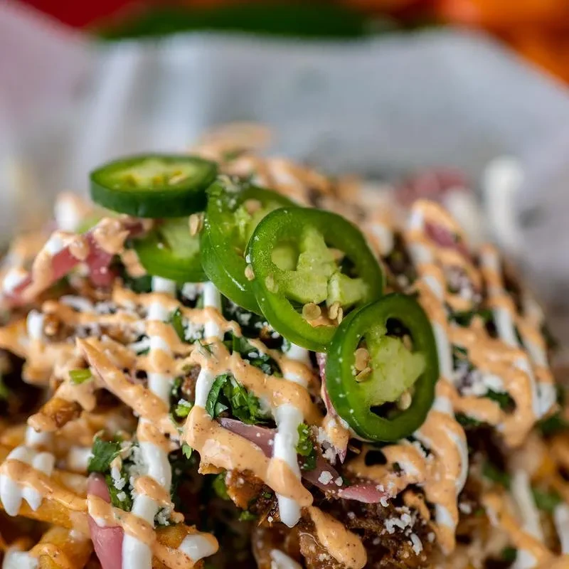 Loaded fries or nachos with meat, cheese, sauces, and jalapeños.