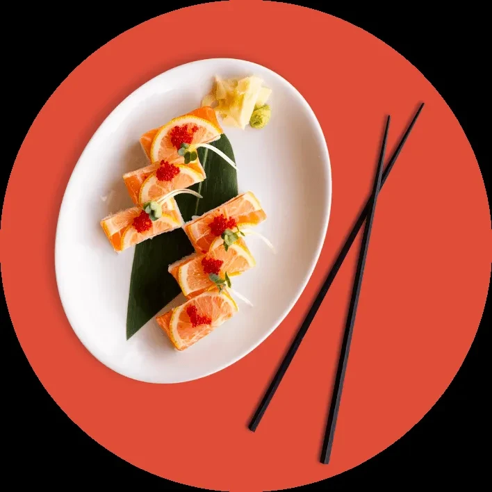 Five sushi rolls topped with citrus and roe, with ginger and chopsticks.