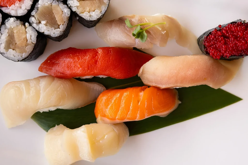 Close-up of vibrant nigiri and maki sushi on a white plate.