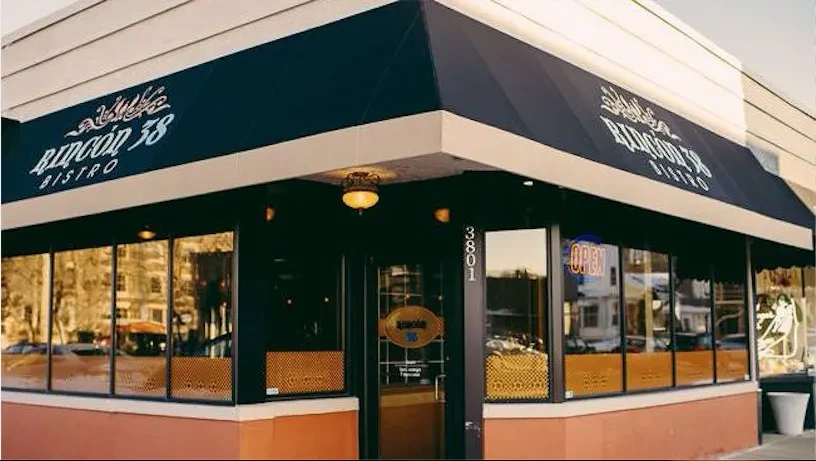 Rincón 38 Bistro: Corner building exterior with dark blue awning, OPEN sign.