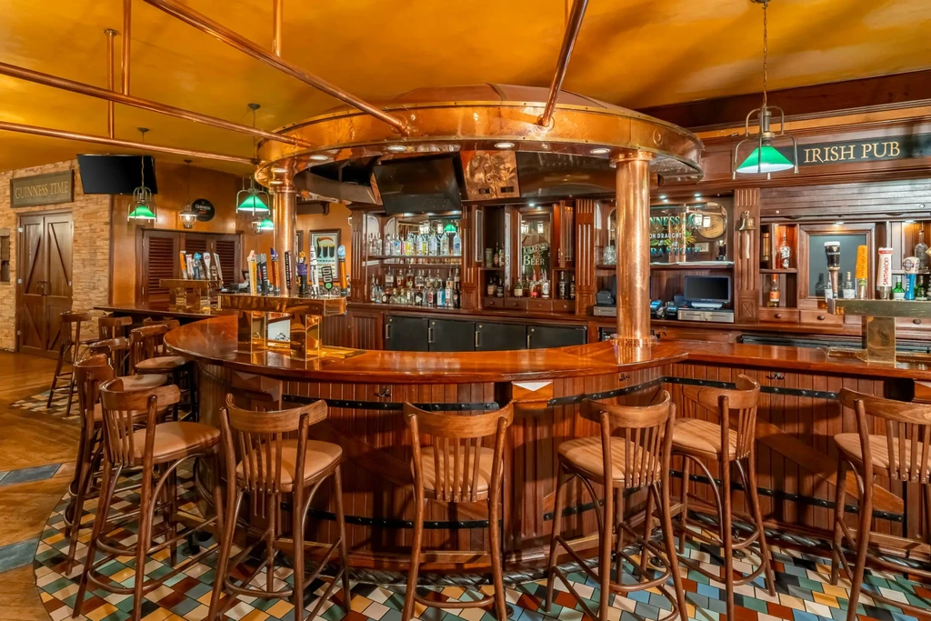 Empty Irish pub interior with a circular wooden bar and prominent copper.