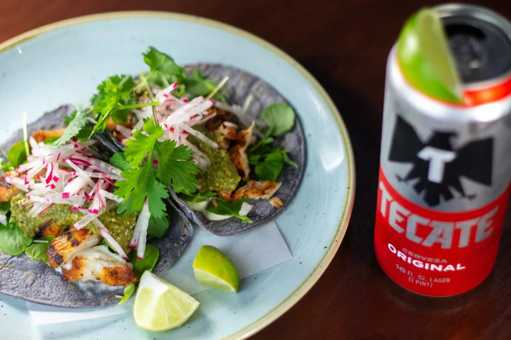 Two blue corn tacos with grilled protein, cilantro, and Tecate beer.
