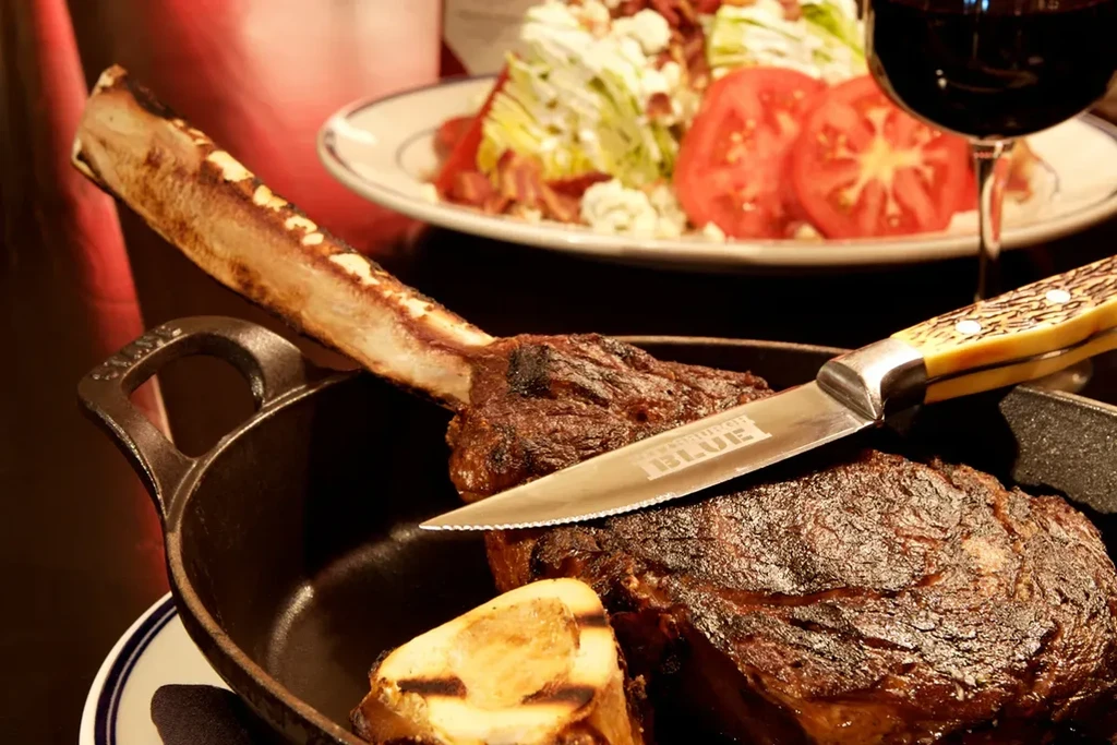 Tomahawk steak, bone marrow, engraved knife, and wedge salad.