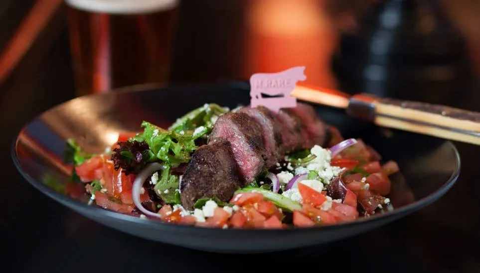 Medium-rare steak salad with feta, tomatoes, and a "RARE" marker.
