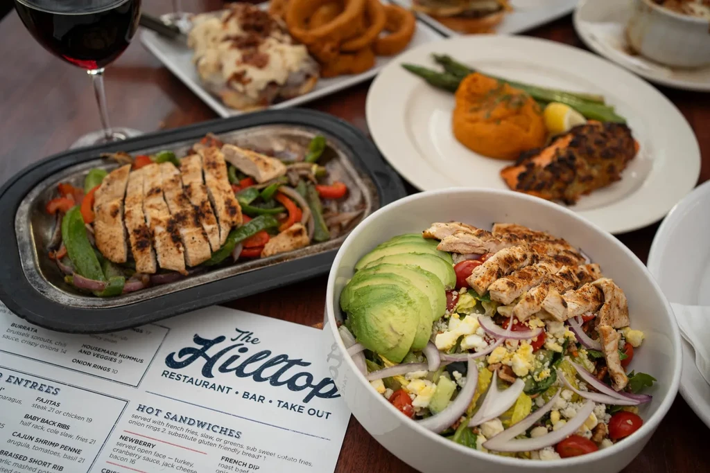 Overhead view: restaurant table with fajitas, chicken salad, salmon, red wine.