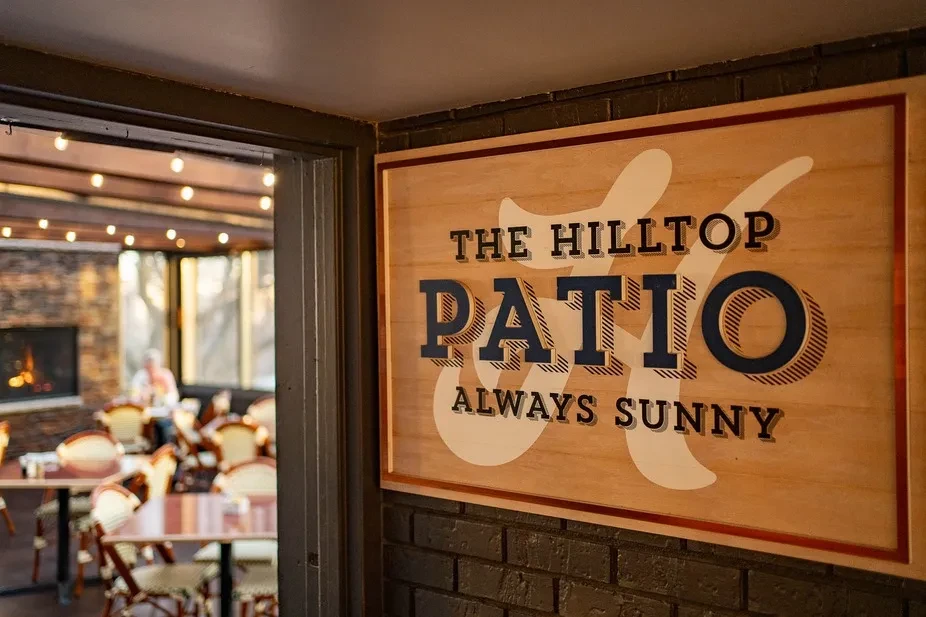 Restaurant interior with a prominent "The Hilltop Patio" wooden sign.