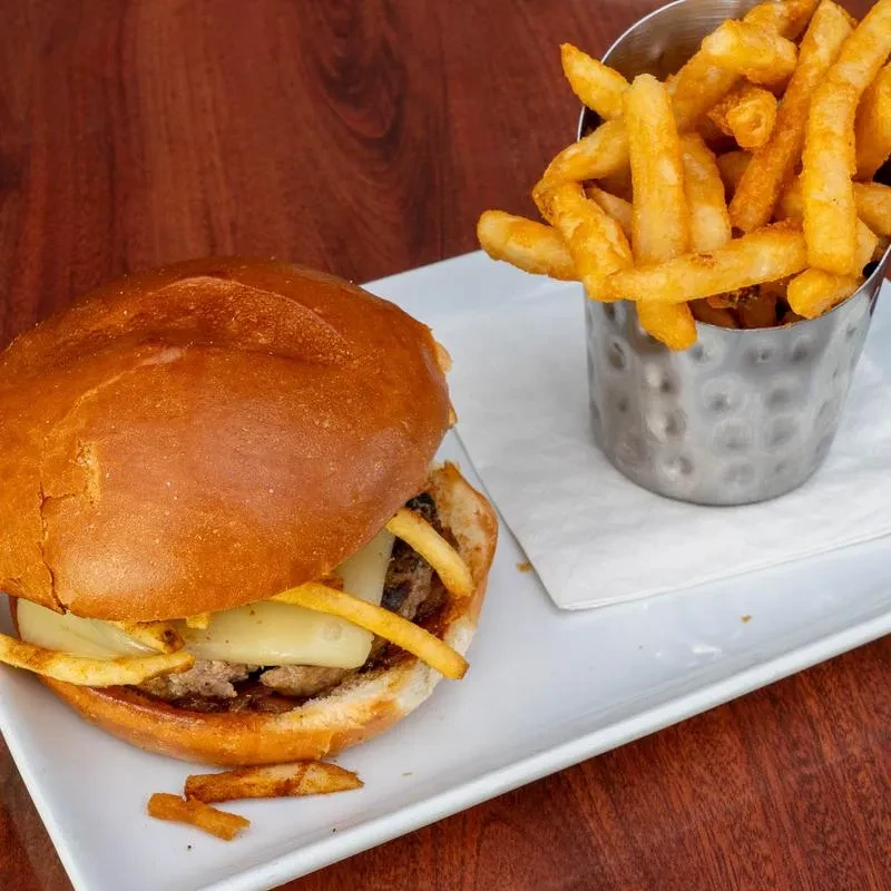 Burger with melted cheese, fries inside, plus a cup of fries.